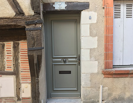 Photo d'une porte d'entrée grise dans un mur en pierre